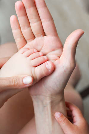 Mother holds her foot with a wounded toeの写真素材