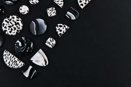 A product from polymer clay. Black and white polymer clay. Hand sculpting, product for earrings on a black background. View from above. Black and white jewelry earrings. Handmade polymer clay jewelry.の写真素材