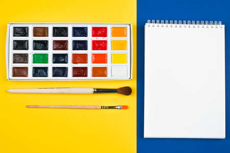 multi-colored paints and brushes on a yellow backgroundの写真素材