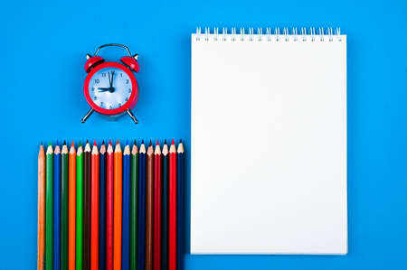 Notebook with colored pencils and a clockの写真素材