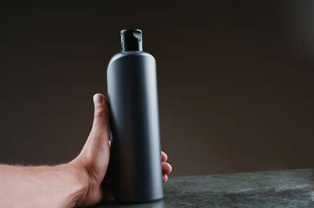mockup of gray plastic bottle in hands on a dark backgroundの写真素材