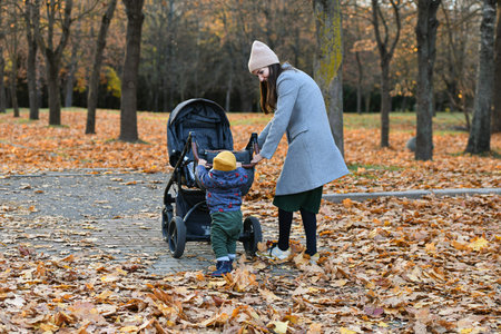 child helps mom push the stroller. High quality photo