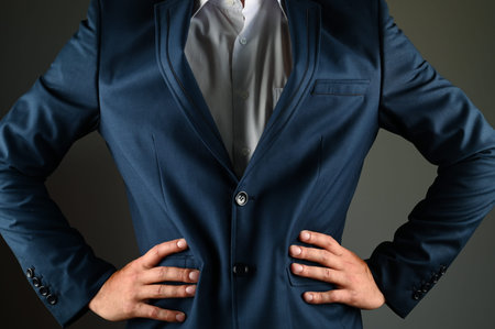 The man in the suit put his hands on his waist. A man in a suit on a black background. Concept:...