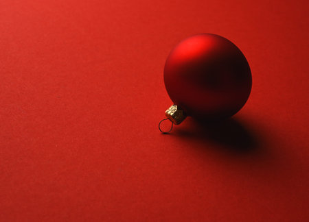Red Christmas ball lies on a red surface with shadows