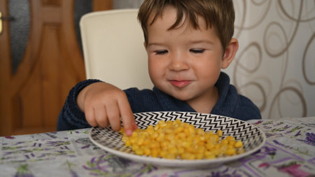 Child eating corn from a plate. High quality photoの写真素材