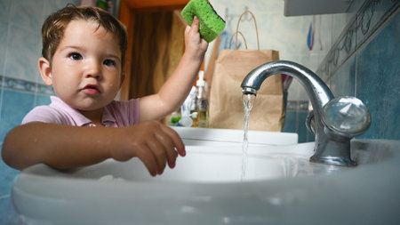 The child near the washbasin conducts hygiene. High quality photoの写真素材
