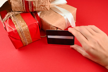 Hand holds a plastic card on the background of gifts. High quality photoの写真素材