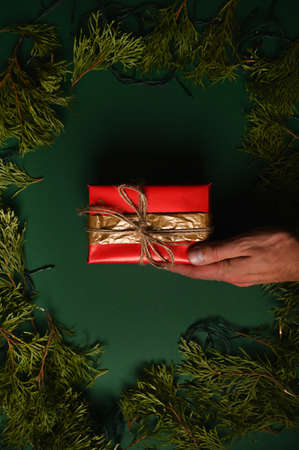 Hand holding a new year gift on a dark green christmas backgroundの写真素材
