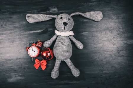 Knitted rabbit toy with red christmas decorations. Christmas background. High quality photoの写真素材
