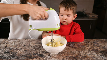 mom shows the child how to work with a mixer. High quality photo