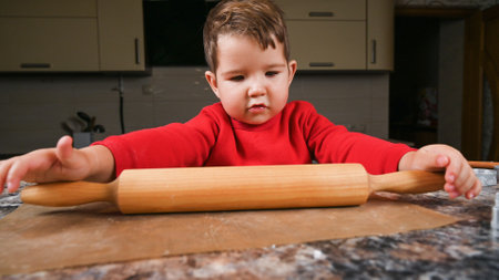 The child learns to roll the dough with a rolling pin. High quality photoの写真素材