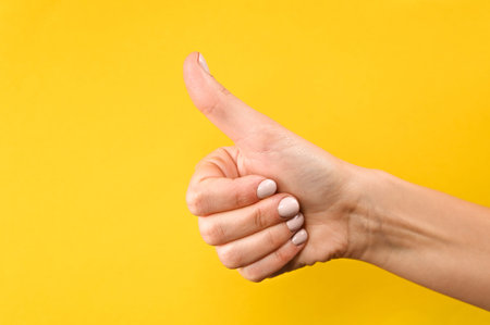 Thumb up on yellow background. High quality photo