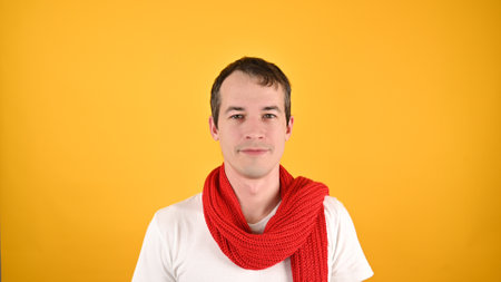 Portrait of handsome young man in red scarf and white T-shirt. Studio shot on a yellow background. Advertising mockupの写真素材