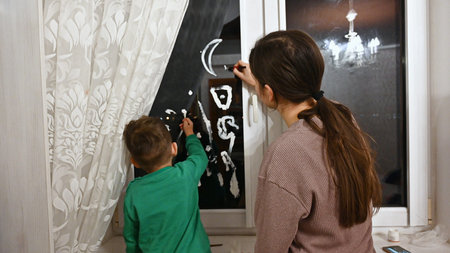 The child with his mother draws on the glass. High quality photo