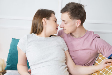 Young pregnant girl kissing her husband. High quality photo