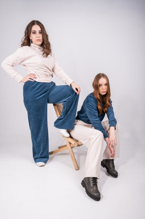 Two young, stylish women looking at camera while posing isolated on white. Female capsule wardrobe...