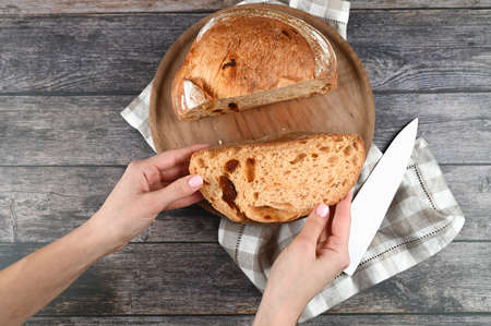 Hands hold cut homemade bread on wooden background. High quality photoの写真素材