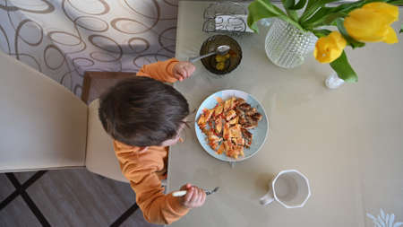The child takes food at the table, top view. High quality photoの写真素材