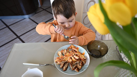 The child takes food at the table, top view. High quality photoの写真素材