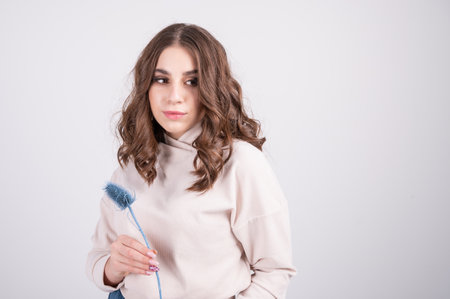 A stylish young girl in a beige clothes holding dried flowers in her hands, white studio background with copy space. High quality photoの写真素材