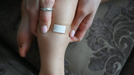 Mother putting bandage or patch on sons leg. Health and pharmaceutical concept, child health...