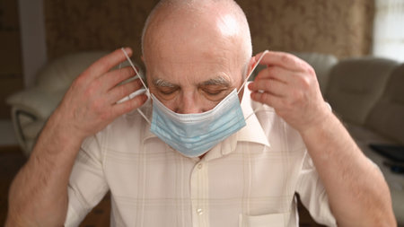 Elderly gray-haired man take off the protective mask. The pandemic ends, difficulty breathing...