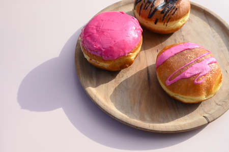 Different colorful donuts and plate on the pink background. Creative food concept. High quality photoの写真素材