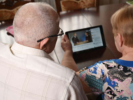 An elderly couple is sitting at a computer and looking for information on the Internet. View from above.の写真素材