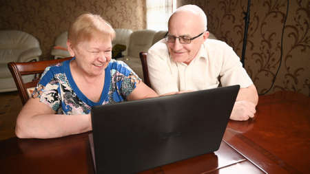 Portrait of happy old senior couple with laptop computer having video call chat. Retirement senior couple old age lifestyle communicating technology connection people conceptの写真素材