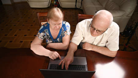 An elderly couple is sitting at a computer and looking for information on the Internet. View from above.の写真素材