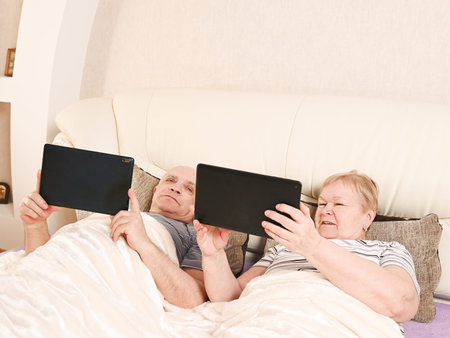 Elderly people look into their mobile gadget.の写真素材