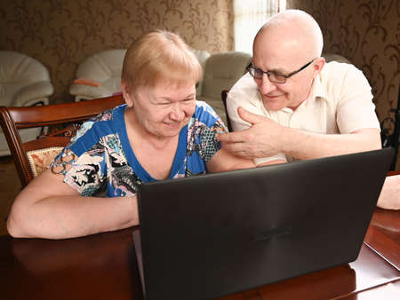 Portrait of happy old senior couple with laptop computer having video call chat. Retirement senior couple old age lifestyle communicating technology connection people conceptの写真素材