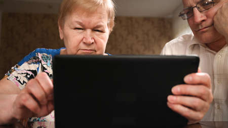 Elderly married couple sitting at the computer makes purchases on the Internet.の写真素材