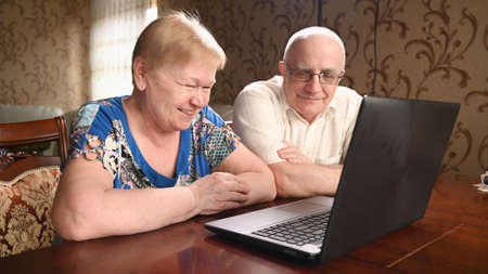 Portrait of happy old senior couple with laptop computer having video call chat. Retirement senior couple old age lifestyle communicating technology connection people conceptの写真素材