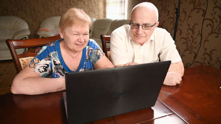 Portrait of happy old senior couple with laptop computer having video call chat. Retirement senior couple old age lifestyle communicating technology connection people conceptの写真素材