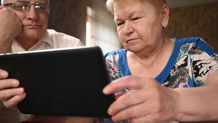 Close up of an elderly couple uses a digital tablet. Communicate connecting technology people. Learning conceptの写真素材