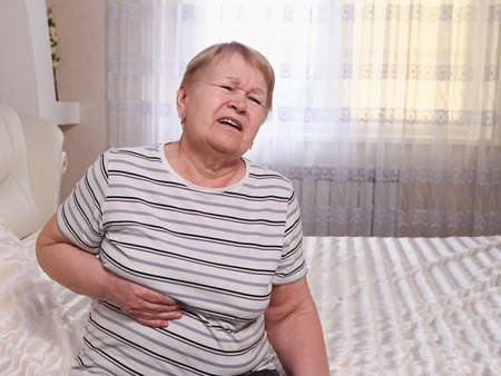 Elderly woman on bed with heartache.の写真素材