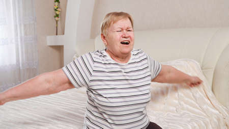 Elderly woman in the bedroom doing exercises.の写真素材