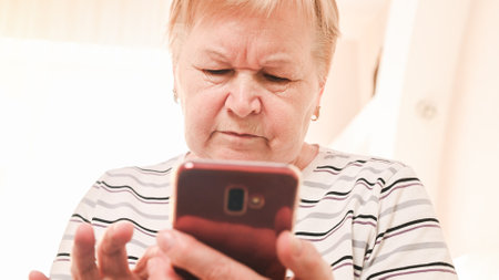 elderly woman with mobile phone at home.の写真素材