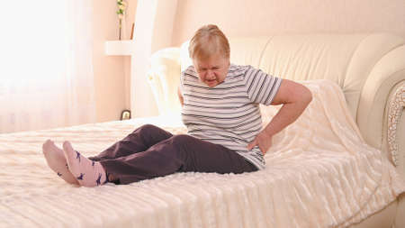 Elderly woman on bed with back pain.の写真素材