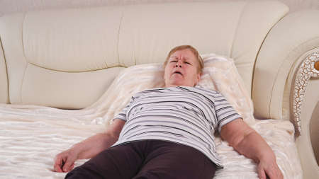 Elderly woman on bed with sore throat.の写真素材