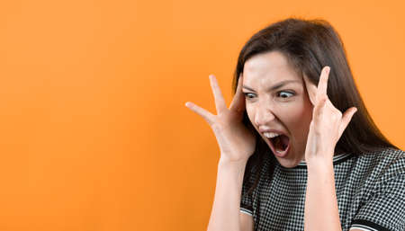 Portrait of an angry young girl on orange background.の写真素材