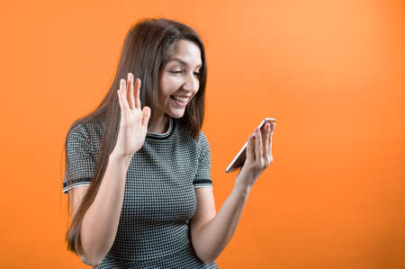 A young girl communicates through a cell phone camera, on a yellow background.の写真素材