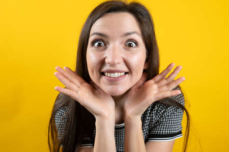 Young girl fooling around, on a yellow background.の写真素材