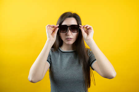 Portrait of a young girl in sunglasses, on a yellow background.の写真素材