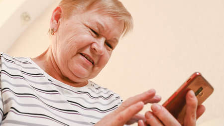 Elderly woman with a phone in her hands, bottom view.の写真素材