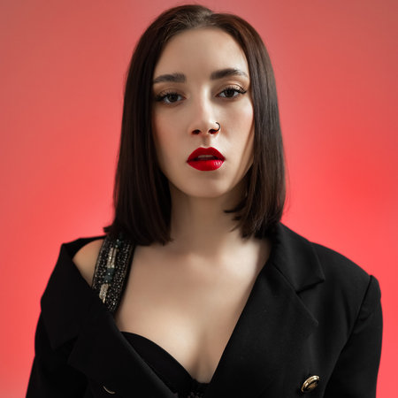 Sexy young woman in black clothes with red lips looking at the camera.