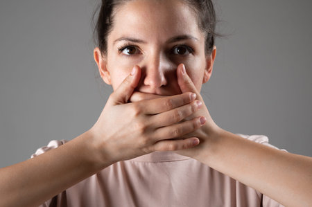 The woman covers her mouth with her hands.の写真素材