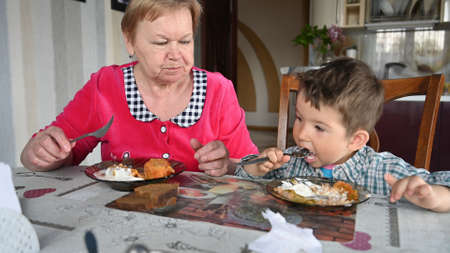 Grandmother and grandson eat at the table.の写真素材