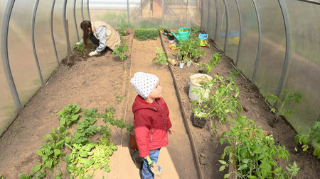 Mom and child take care of plants in the greenhouse.